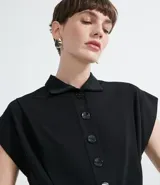 Mono largo de malla jersey color negro, con cuello tipo camisa, cierre frontal abotonado, sin mangas y cinturón de la misma tela para ajustar en la cintura.