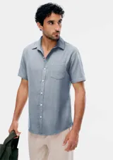 Camisa de manga corta celeste con estampado de micromercado, cuello camisero, cierre frontal con botones y un bolsillo ojal en el pecho.