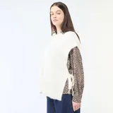 Sweater sin mangas de tejido de punto en color beige, con cuello redondo y diseño holgado con aberturas laterales ajustables mediante lazos.