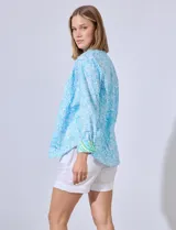 Camisa de algodón estampada en tonos celeste y blanco, con cuello con solapa, abertura central con botones y mangas largas con puños en contraste.