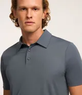 Camisa polo masculina de manga corta, confeccionada en tejido técnico de poliamida con elastano. Presenta cuello inglés con cierre de botones y diseño liso en color marrón, con tecnología de secado rápido y confort térmico.