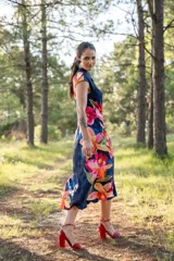 Vestido midi azul marino con estampado de flores rojas, naranjas y rosas. Tiene cuello drapeado y corte ajustado al cuerpo.