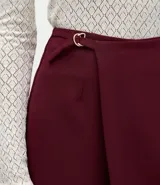Short pollera de sastrería confeccionado en crepé, con diseño de frente traspasado, cintura alta estructurada y detalle de hebilla metálica lateral.