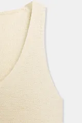 Top de punto sin mangas, color blanco y negro, con escote redondo y diseño a rayas horizontales.