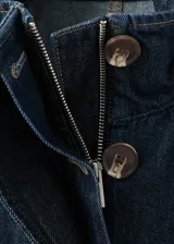 Parka oversize de tejido denim color azul oscuro, con cuello alto, mangas raglán largas, bolsillos laterales, cintura elástica y cierre frontal con botones ocultos.