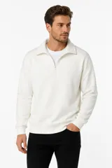 Sudadera de cuello polo con cierre frontal parcial, manga larga y puños acanalados, en color crudo.