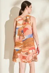 Vestido corto de lino italiano, sin mangas y con cuello redondo, de corte recto y estampado abstracto en tonos tostado, coral, marrón y azul. Cuenta con costuras con detalles desflecados en la parte frontal.
