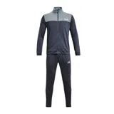 Conjunto deportivo Under Armour compuesto por una campera con cierre frontal y cuello alto, y un pantalón de jogging a juego. La campera presenta un diseño bicolor con la parte superior en gris y el resto en azul marino, mientras que el pantalón es de color azul marino. Ambas piezas incluyen el logo de la marca estampado en blanco.
