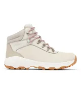 Bota de trekking Columbia para mujer, confeccionada en ante impermeable color crema con detalles en gris claro. Presenta herrajes metálicos, cordones jaspeados en tonos rosados y suela de caucho con tecnología de alta tracción.