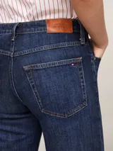 Jean de denim azul oscuro, de corte recto y talle medio, con efecto gastado en la parte delantera, cinco bolsillos y logo de Tommy Hilfiger bordado en el bolsillo trasero.