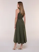 Vestido midi sin mangas de color verde militar, confeccionado con la parte superior en tejido de punto acanalado con cuello alto y falda acampanada de gran vuelo.