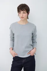 Remera de manga larga con cuello redondo, confeccionada en tejido de punto gris melange con costuras visibles en contraste.