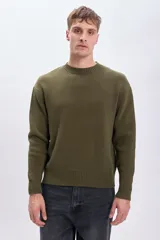 Sweater de punto color verde oliva, con cuello redondo y mangas largas. Diseño clásico con terminaciones acanaladas en cuello, puños y ruedo.