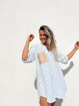 Camisola de corte oversize con estampado de rayas verticales azules sobre fondo blanco. Presenta cuello camisero, cierre frontal con botones y dos bolsillos frontales en contraste de color beige con acabado tipo gamuza.