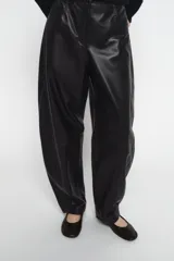 Pantalón barrel negro de piel 100%, tiro medio con cintura con trabillas, cinco bolsillos y cierre frontal con cremallera y botón.