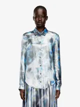 Camisa Diesel C-Ronor-S2 de mujer, manga larga, confeccionada en tejido fluido y semitransparente con acabado metalizado y estampado abstracto de efecto acuarela en tonos azules, plateados y blancos. Presenta cuello clásico y cierre frontal de botones.