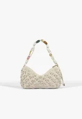 Cartera baguette de cuero color beige con diseño trenzado tipo red y apliques de cuentas de colores y formas metálicas en el cuerpo y en la manija. Cuenta con cierre superior y etiqueta colgante de la marca.