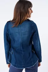 Chaqueta de estilo victoriano confeccionada en tejido denim azul, con cuello mao y cierre frontal de doble botonadura con botones plateados. Presenta bordes deshilachados y corte ajustado que realza la figura.