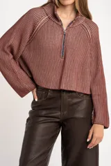 Sweater marrón de punto acanalado, con cuello alto, cierre frontal parcial con cremallera y manga larga.