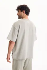 Remera oversize gris oscuro con efecto lavado, cuello redondo y mangas cortas amplias.
