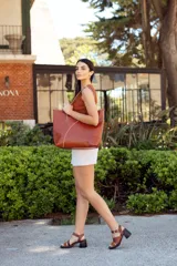 Bolso tote de cuero color marrón con costuras blancas a contraste. Tiene doble asa de hombro y diseño minimalista.