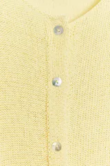 Chaqueta de punto rústico color amarillo claro, con cuello redondo, manga larga y cierre frontal con botones nacarados.