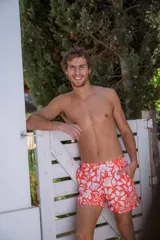 Short de baño rojo con estampado de hojas blancas, cintura elástica con cordón ajustable y bolsillos laterales.