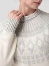Sweater de punto con diseño jacquard circular en el yugo, mangas y ruedo. Presenta cuello redondo, mangas largas y puños acanalados en un tono beige claro con detalles en gris.