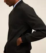 Campera estilo bomber de color negro, confeccionada con tejido repelente al agua. Posee cuello semi alto, cierre frontal con cremallera, bolsillos laterales y puños y dobladillo elastizados. Marca Marfinno.