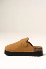 Zueco de plataforma color camel, confeccionado en material tipo gamuza, con detalle de hebilla metálica lateral y base de corcho con suela de goma negra.