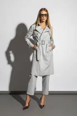 Trench gris con cuello solapa, doble botonadura, cinturón con hebilla y bolsillos laterales.