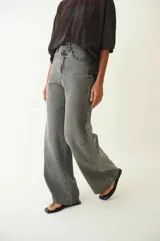 Pantalón de jean con corte baggy de tiro medio, diseño de cinco bolsillos y acabado desgastado en tono gris oscuro.