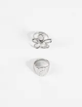 Set de dos anillos plateados de zinc. Uno con forma de flor y otro con forma de sello circular con textura machacada.