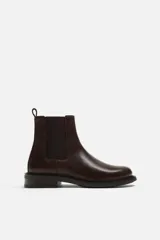 Bota tipo Chelsea de piel color marrón oscuro, con paneles elásticos laterales, tirador trasero y suela de goma con ligero tacón.