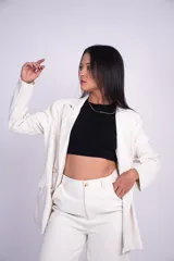 Blazer levemente largo de color beige con solapas de muesca, doble botonadura frontal de cuatro botones, hombreras y bolsillos delanteros ribeteados con solapa.