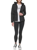 Campera ligera Calvin Klein de técnica mixta, con cuerpo acolchado y mangas lisas. Presenta cuello alto con capucha, cierre frontal de cremallera y bolsillos laterales con cierre.