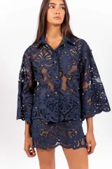 Camisa de molde clásico confeccionada en encaje bordado tipo guipur, color azul, con mangas largas amplias y aplicación de tachas doradas.