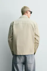 Sobrecamisa de corte regular fit en color beige, confeccionada en popelín de algodón. Cuenta con cuello solapa, manga larga con puño abotonado, bolsillos ocultos en las costuras de la cadera y cierre frontal con botonadura oculta.