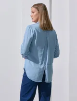 Camisa gris de tencel con cuello con solapa, escote en V y abertura central con botones. Largo de manga regulable con presilla y botón. Ruedo en espalda con tajo.