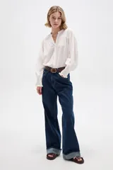 Pantalón de jean azul oscuro, de corte recto y tiro alto, con botamanga rebatida.
