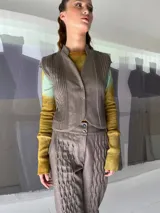 Chaleco de lana texturizada color marrón con alforzas en los laterales, cuello alto y pequeñas mangas.