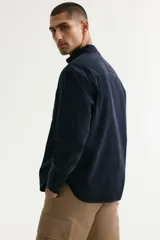 Camisa de pana de algodón suave color negro, con cuello americano, bolsillo superior en el pecho y cierre frontal de botones.