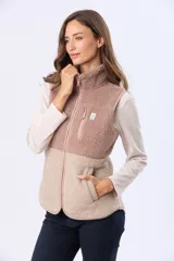 Chaleco de sherpa combinado en tonos beige, con cuello alto y cierre frontal. Presenta una textura suave y abrigada, ideal para capas adicionales.