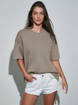 Short de jean blanco con tachas doradas decorativas en los bolsillos delanteros y en los laterales, talle medio y cierre frontal con botón y cremallera.