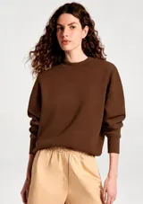 Buzo de cuello redondo en color marrón chocolate, con diseño de corte holgado y puños y ruedo acanalados.