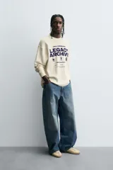 Camiseta de manga larga con cuello redondo, corte relaxed fit y tejido con estructura waffle. Presenta estampados y bordados combinados a contraste en el delantero.