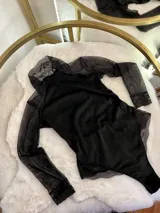 Body de manga larga confeccionado en una combinación de terciopelo, encaje y microtul. Presenta cuello alto, mangas de tul transparente con puños de encaje y detalles de encaje en la zona de la cadera.