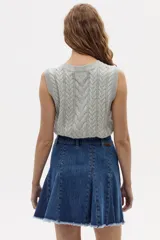 Chaleco de punto color gris melange, con cuello redondo, sisa amplia y largo a la cadera. Presenta un diseño de ochos tradicionales.