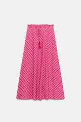 Falda midi con silueta evasé y estampado de cuadros en tonos fucsia y blanco. Presenta cintura elástica con lazo ajustable y detalle de borlas colgantes.