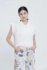 Chaleco tejido color marfil con cuello en V, sin mangas y tajos laterales.